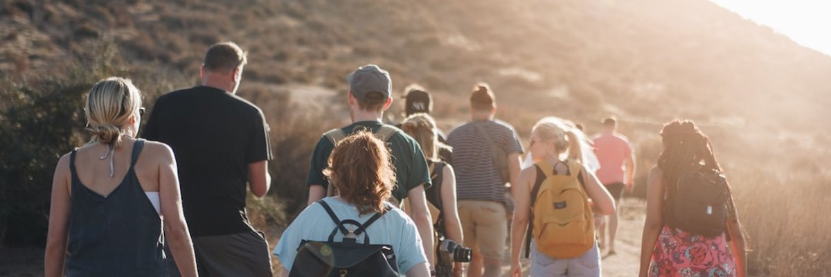 people walking on dirt road near mountain during daytime